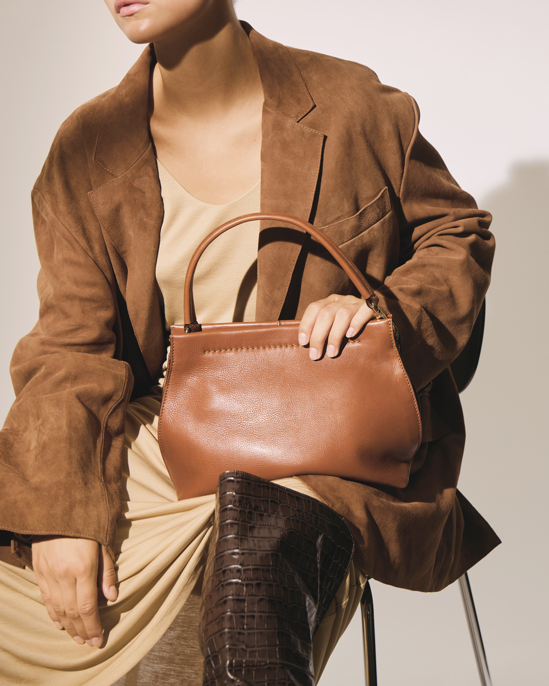 Petra skuldertaske og crossbody i cognacfarvet læder, båret af model med justerbar rem