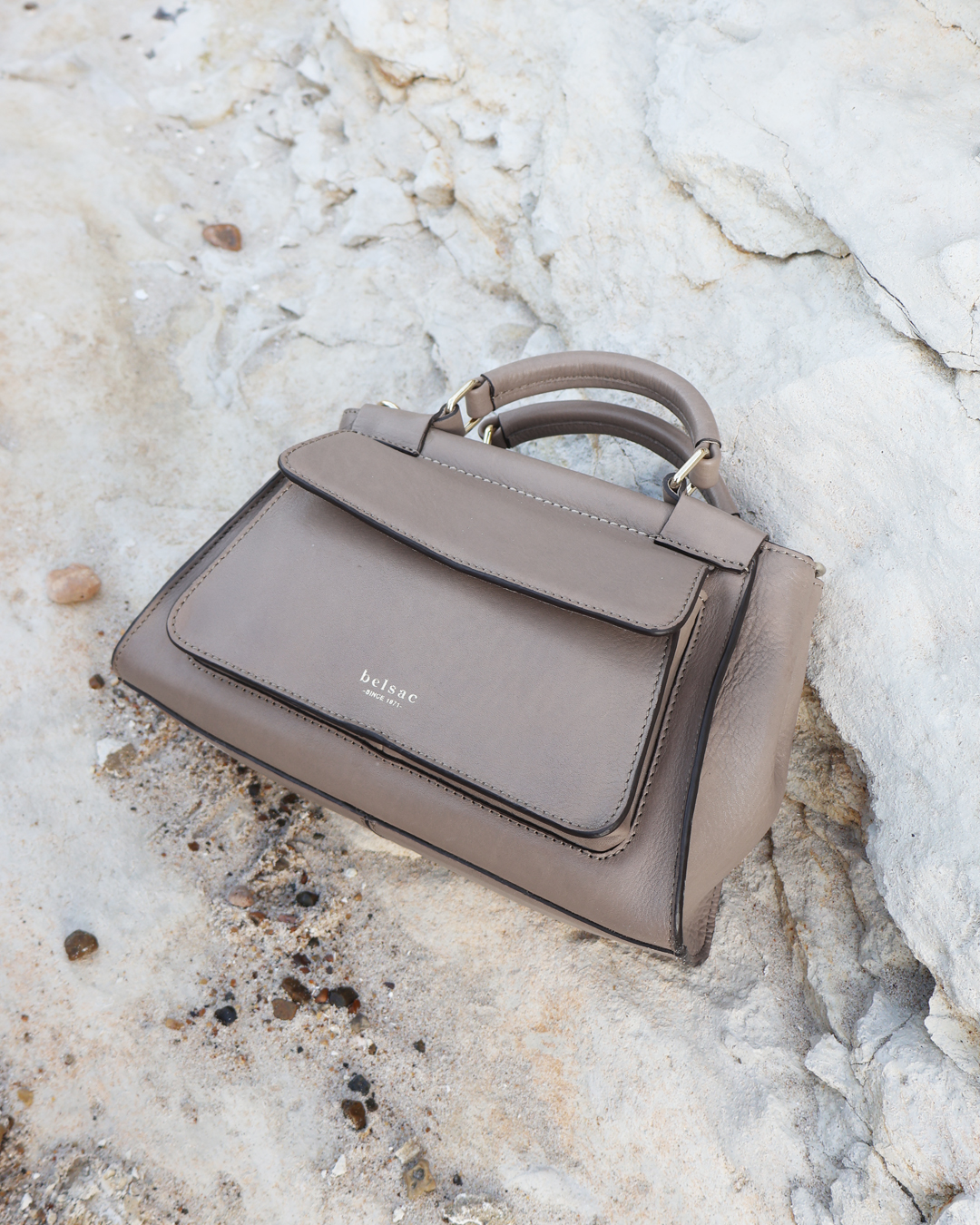 Rachel taupe Crossbody taske i laeder 26501 5 liggende paa hvide sten Belsac Creative